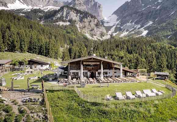Holzliegen laden auf der großen Sonnenterrasse der Wochenbrunner Alm zum Relaxen ein.